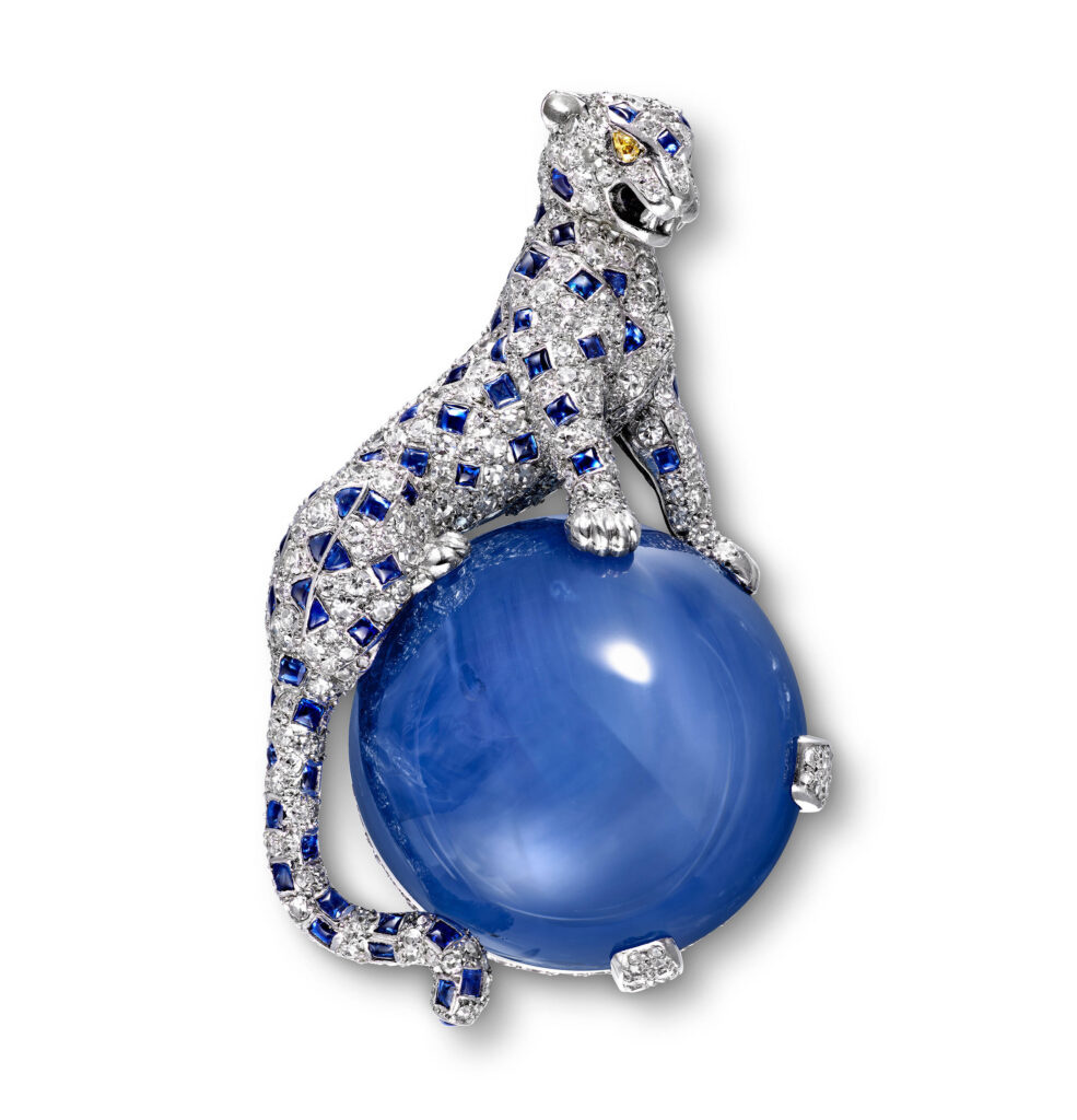 Cartier Brooch featuring jewel-encrusted panther sat on a large blue circular stone